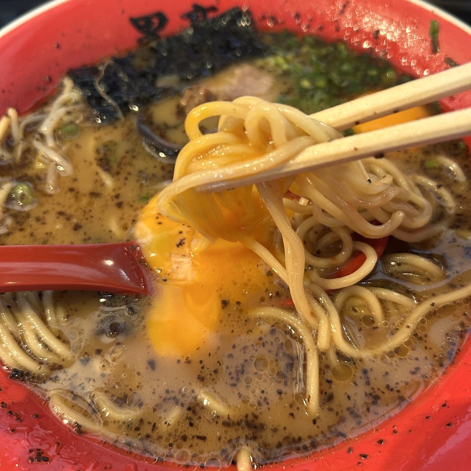 黒亭の玉子入りラーメン。箸で麺と卵黄を絡めて味変を楽しむ瞬間