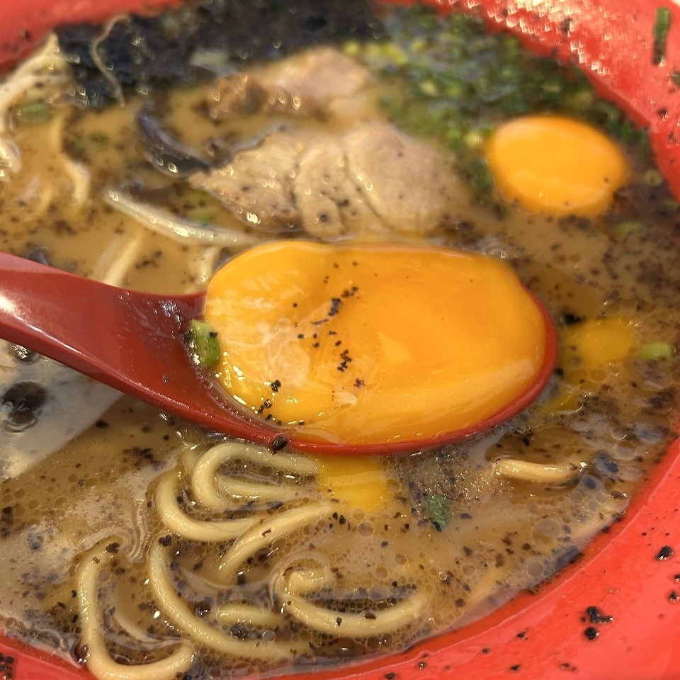 玉子入りラーメンの卵黄をレンゲですくっている様子。味変に最適