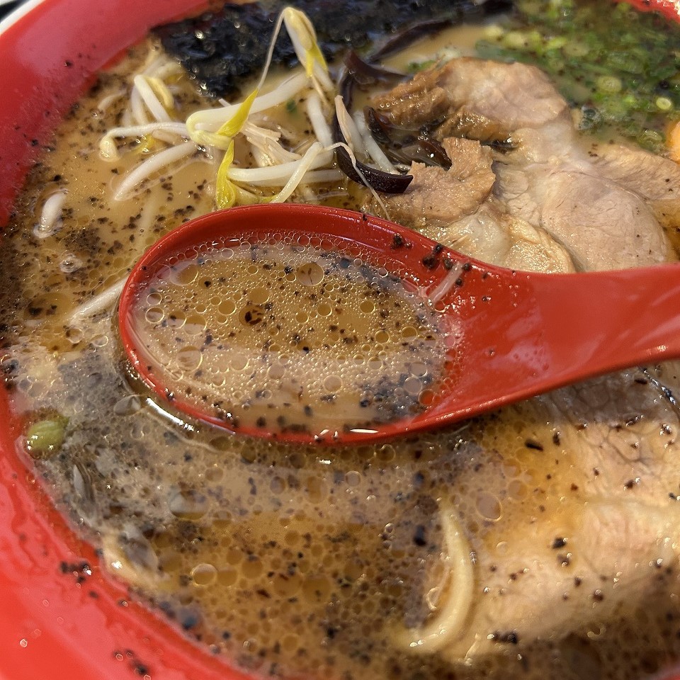 焦がしニンニク香るスープをレンゲですくった写真